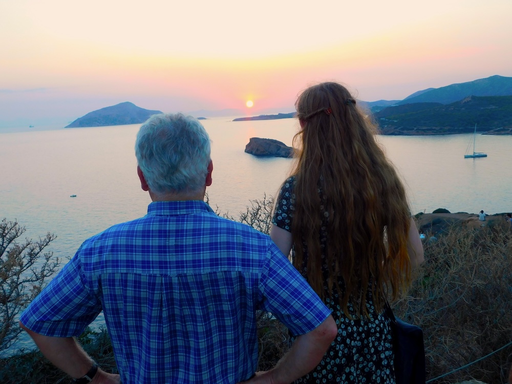 a dad and teen watch the sunset from cape sounion, outside of athens. 