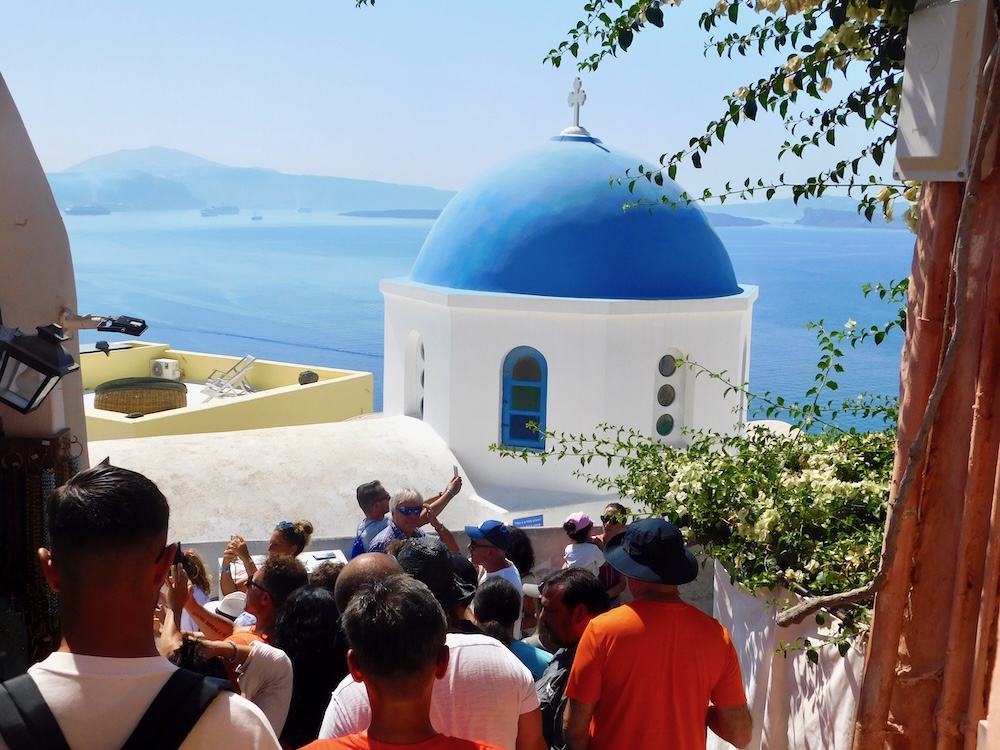 A santorini port day is likely to include views of beautiful blue-domed churches, sea views, and crowded vying for photos of these things.