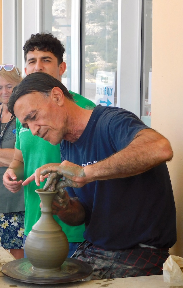 A worker makes a vase on a pottery wheele