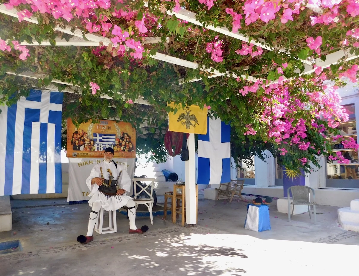 Santorini & Rhodes Port Days Your Teen Might Just Love: a musician takes a break in the shade of magnolia trees in Oia, Santorinia, Greece