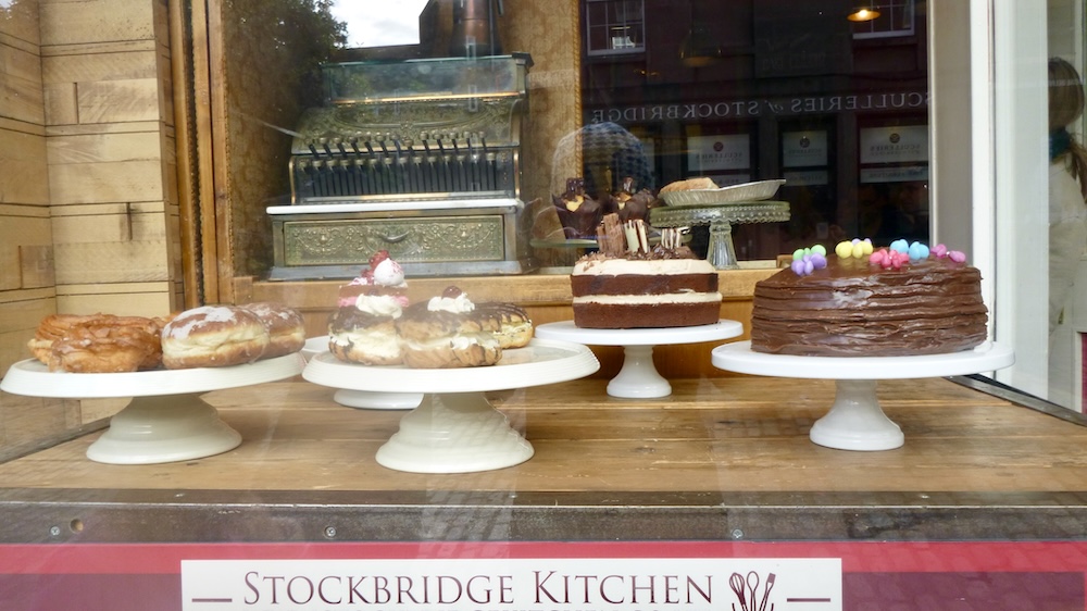 A window full of cakes, cream puffs and an old-fashioned cash register on the stockbridge high street in edinburgh.