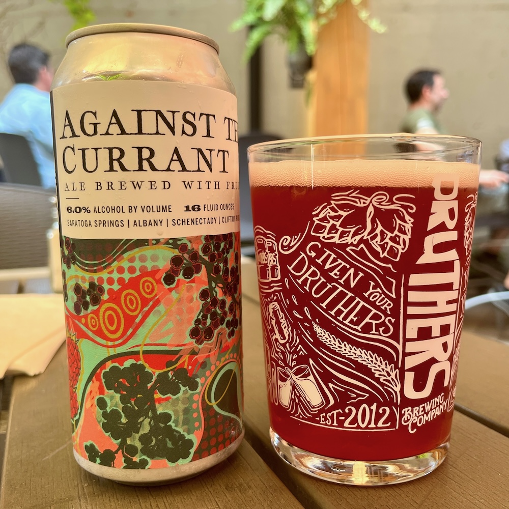A can and glass of druthers summery, pink currant beer.