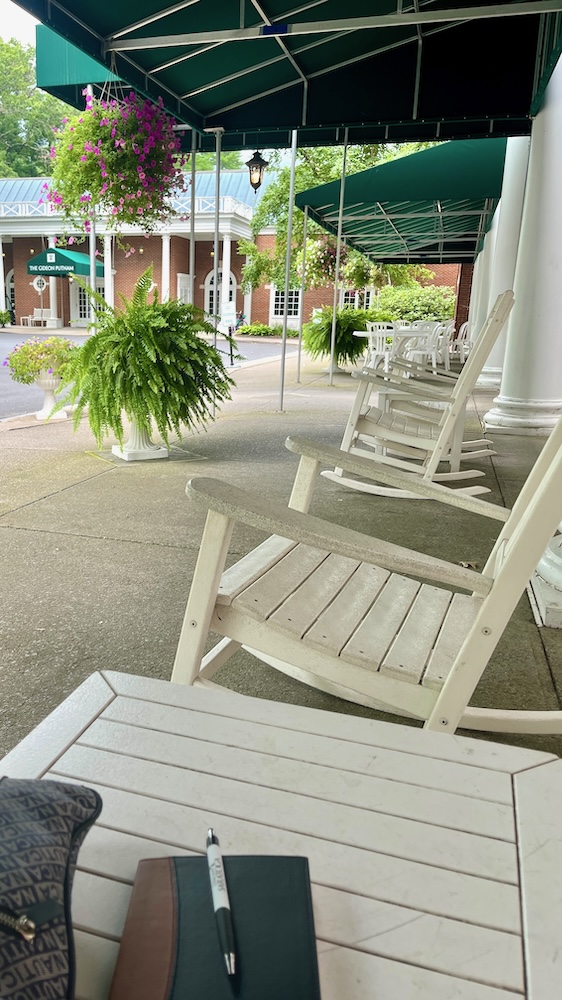 The front porch of the gideon putnam hotel has rocking chairs that invite you to relax.